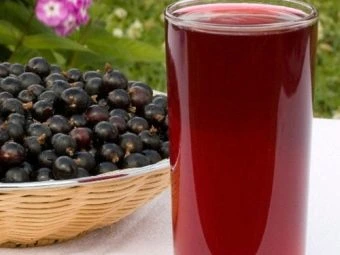 Sklenice červeného rybízového kompotu vedle košíku čerstvých bobulí.