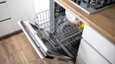 Otevřená myčka s nádobím u dřevěné pracovní desky.