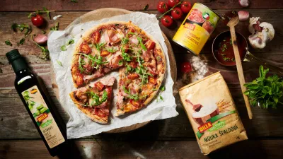 Přes noc skladovaná pizza s ingrediencemi na dřevěném stole.