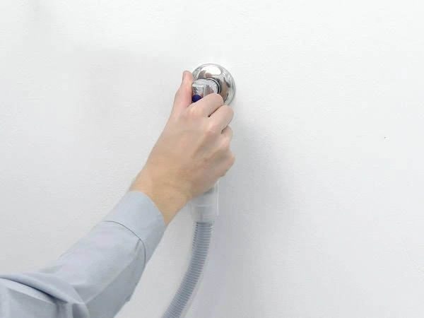 Ruka otáčí kohoutek na myčce s flexibilním hadicovým připojením.