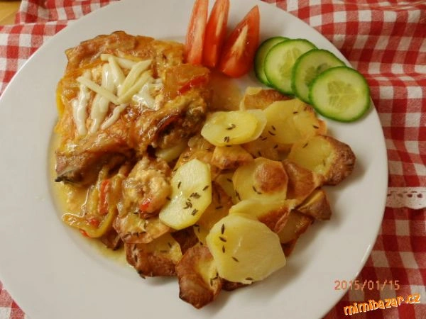 Pečené kuřecí stehna s bramborami a zeleninou na talíři.