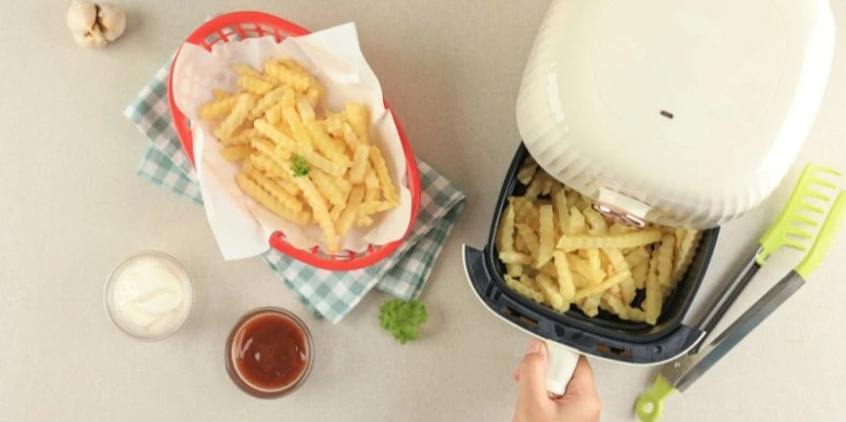 Zlaté bramborové tyčinky z fritéry s omáčkami vedle.
