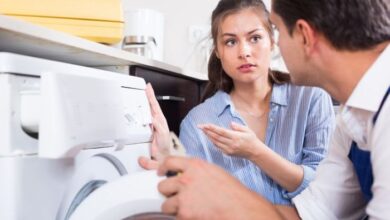Žena se dívá na opravu pračky technikem s kleštěmi.