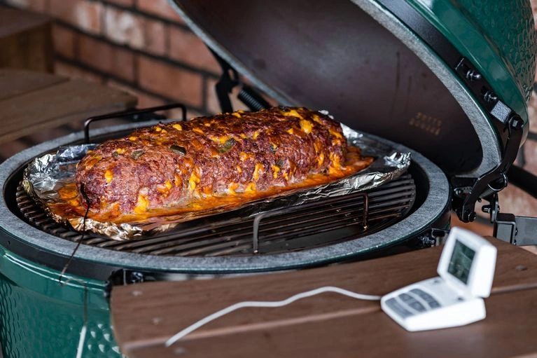 Připravené maso na grilu s teploměrem pro kontrolu vnitřní teploty.