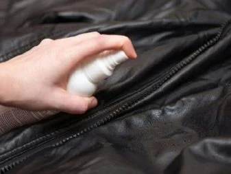 Ruka sprejuje čisticí prostředek na zip koženkové bundy.
