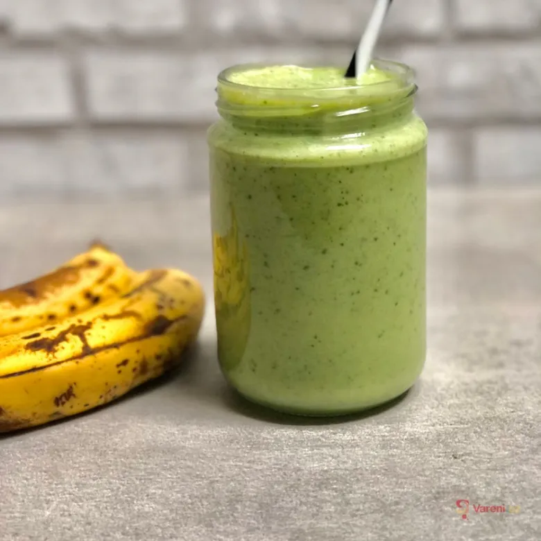 Zelené banánové smoothie v sklenici vedle dvou zralých banana.