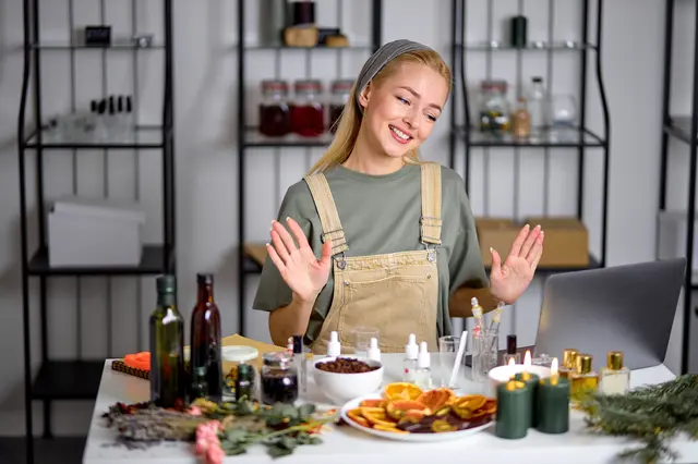 Žena připravuje přírodní domácí vůni s ingrediencemi na stole.