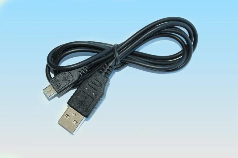 Černý USB kabel pro přenos souborů mezi počítačem a notebookem.