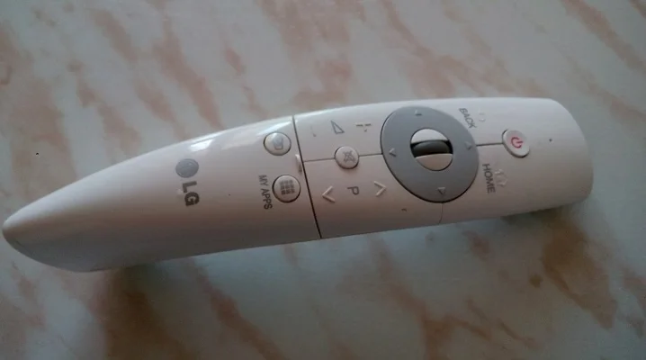 Bílý dálkový ovladač televizoru značky LG ležící na mramorové ploše.