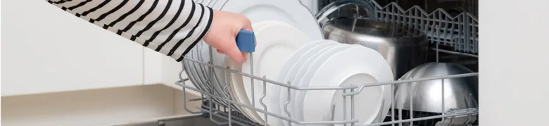 Ruka ukládá čisté talíře do horního koše myčky nádobí.