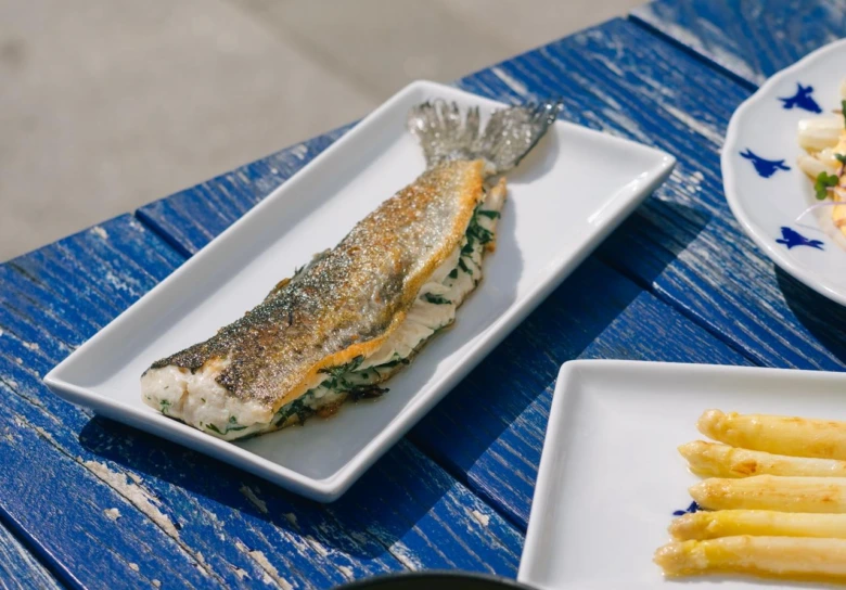 Upečený rybí filet s bylinkami na bílém talíři.
