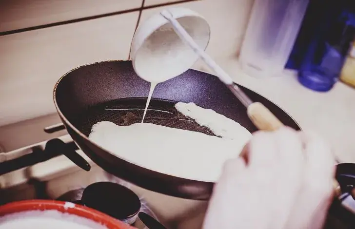 Lévač nalévá palačinkové těsto na pánev.
