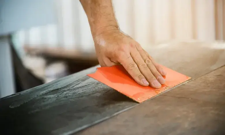 Ruka šlape dřevěnou sudovou prkno oranžovým brusným blokem.