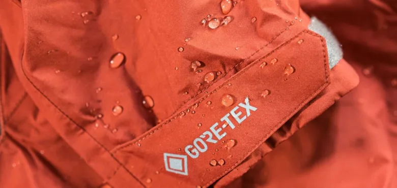 Červená myslivecká bunda s logem Gore-Tex pokrytá kapkami vody.