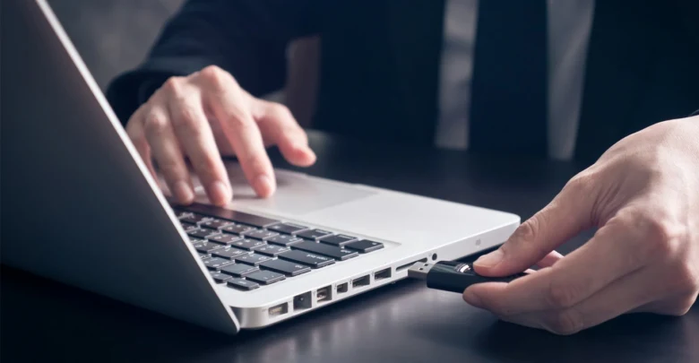 Ruka vkládá USB disk do počítače pro přenos dat.