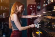 Baristka připravuje espressa v kávovaru s tlakem.