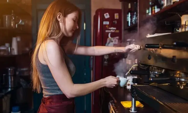Baristka připravuje espressa v kávovaru s tlakem.