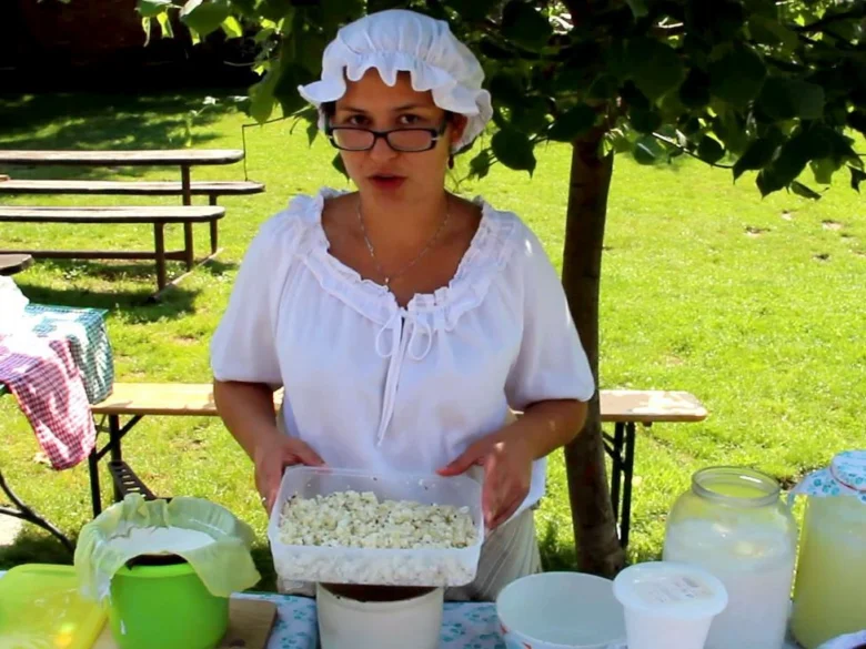 Žena připravuje domácí tvaroh na venkovním stole.