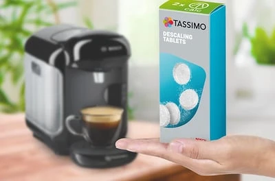 Ruka drží krabičku tabletů na čištění kávovaru Tassimo.