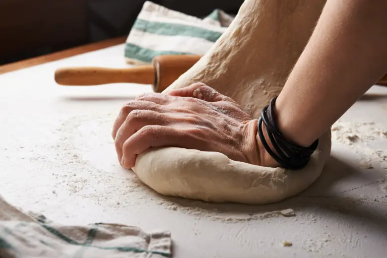 Ruční tvarování těsta na pizzu před pečením.