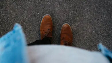 Hnědé boty ze semiše na asfaltu z pohledu shora.