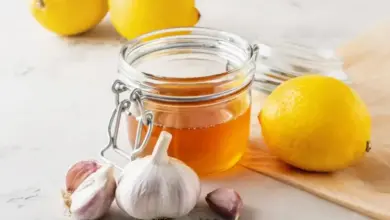 Sklenice medu s citronem a cesnekem na mramorove ploche.