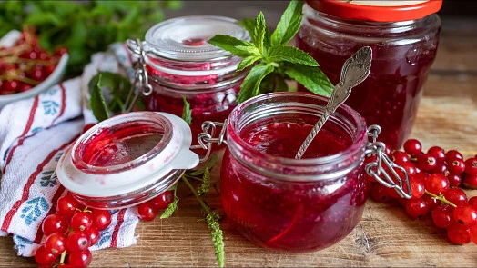 Sklenice červené rýže s marmeládou, čerstvé bobule a máta na dřevě.
