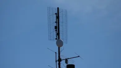 Televizní anténa na střeše domu pod modrou oblohou.