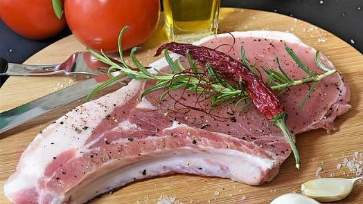 Surové vepřové stehno s bylinkami na dřevěném prknu.