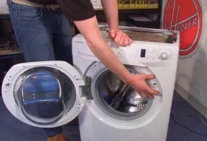 Muž kontroluje vnitřek bílého pračky s otevřenou dvířky.