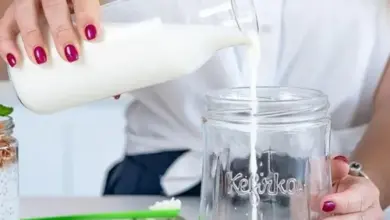 Lidka nalévá bílý kefír z láhve do sklenice.