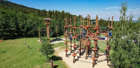 Venkovní park s dřevěnými překážkami uprostřed zelené trávy.