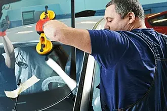 Mechanik montuje nové auto sklo v dílně bez použití leštění.