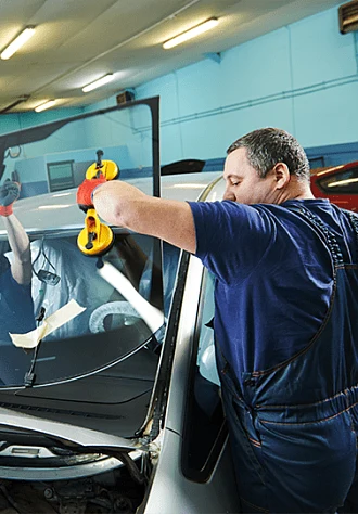 Mechanik montuje nové auto sklo v dílně bez použití leštění.