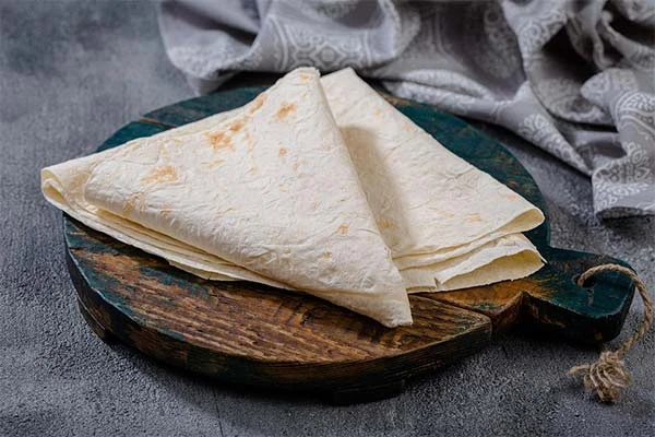 Skládaný chléb lavash na dřevěném podnosu.