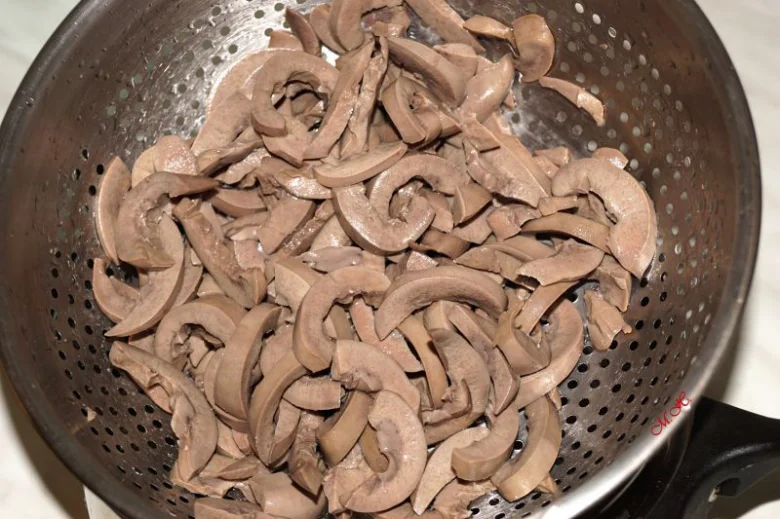 Nakrájené vepřové ledviny odtékající ve cedníku.