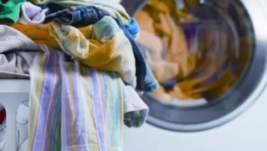 Barevné prádlo na košíku před zamčenou pračkou.