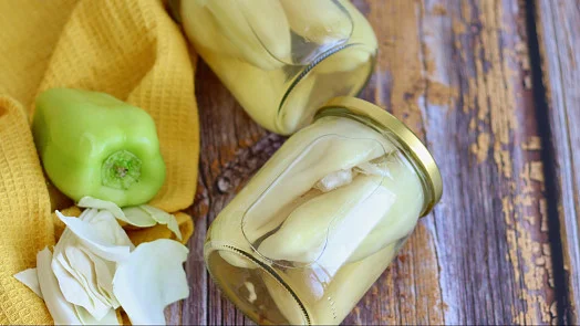 Čerstvá zelená paprika s česnekem v sklenicích na dřevěném povrchu