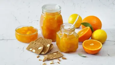 Sklenice s pomerančovou marmeládou vedle čerstvých citrusů.