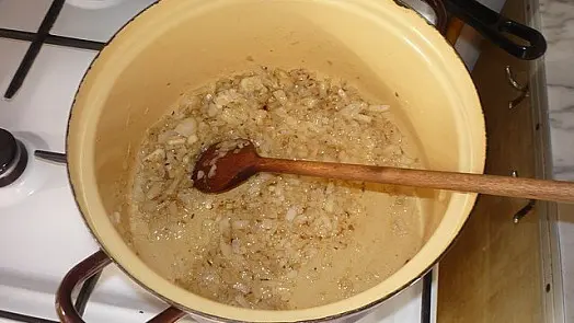 Smažené cibule v hrnci na sporáku pro guláš.