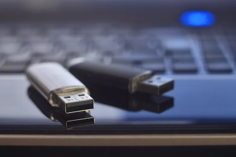 Dva USB klíče na povrchu před počítačem.
