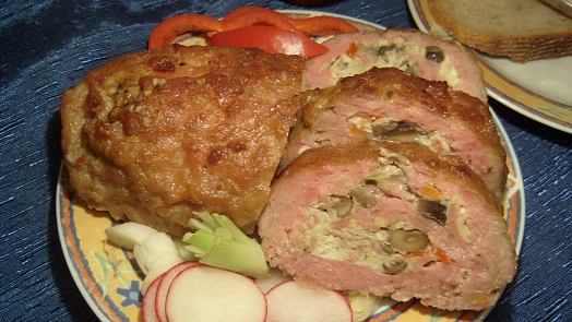 Na talíři jsou nakrájené rolády s náplní, okrazeny zeleninou.