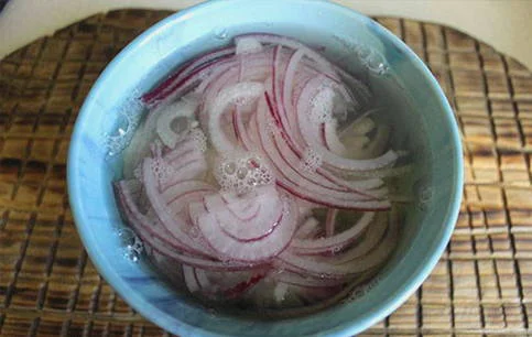 Červená cibule nakrájená na plátky namořená ve vodě.