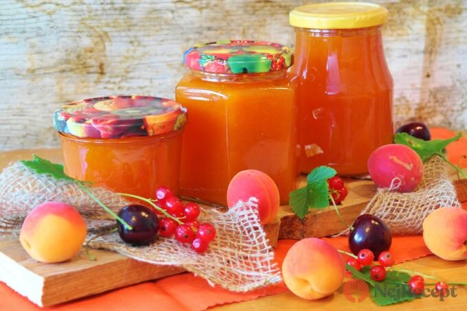 Sklenice s broskvovou marmeládou a čerstvé ovoce na dřevěném podkladu.