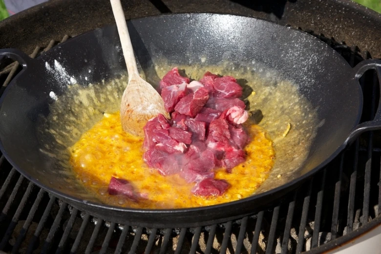 Surové maso se vaří v páni na grilu.